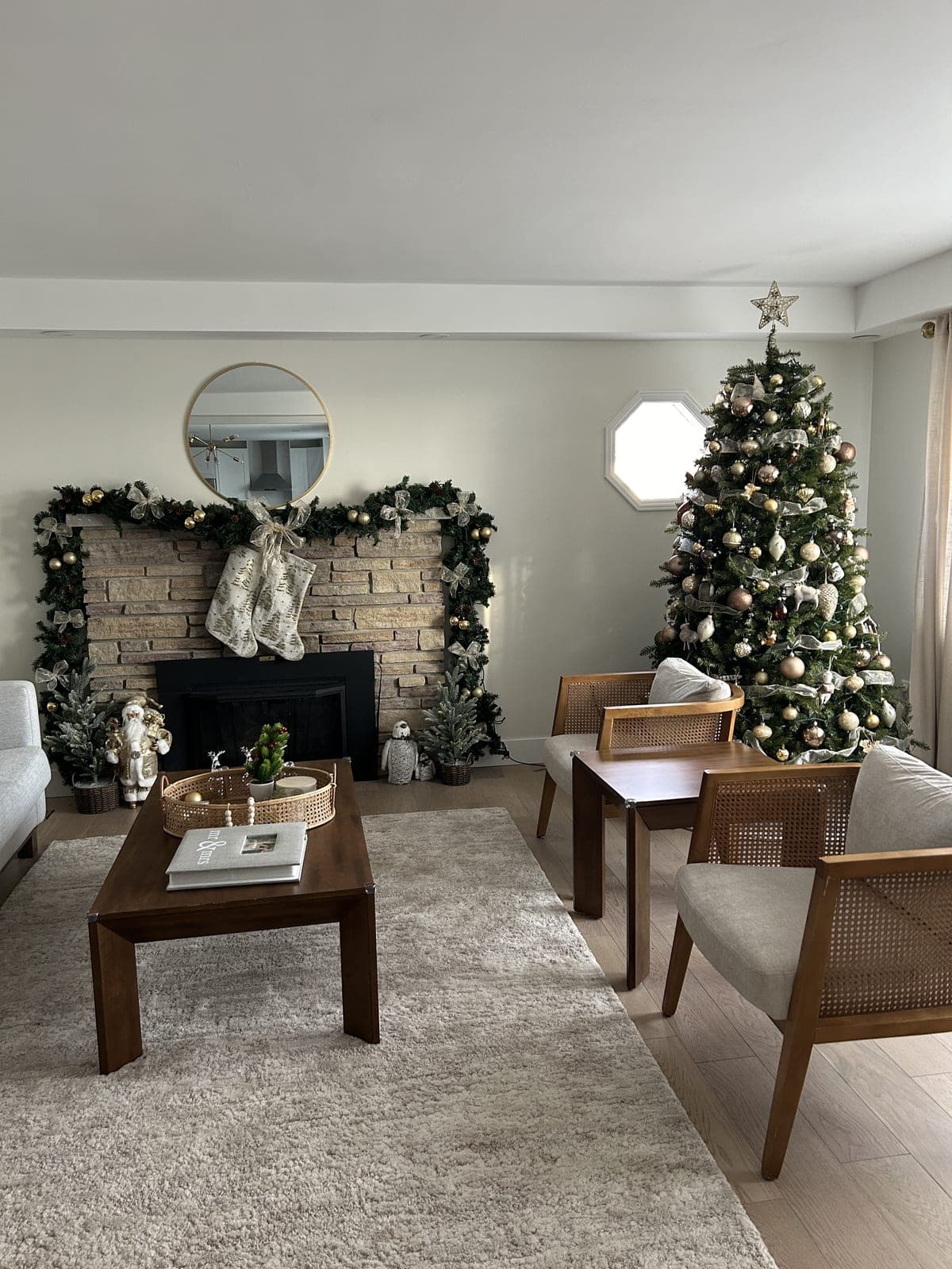 Cozy living room Christmas tree next to a fireplace mantel with lit garland and hanging stockings