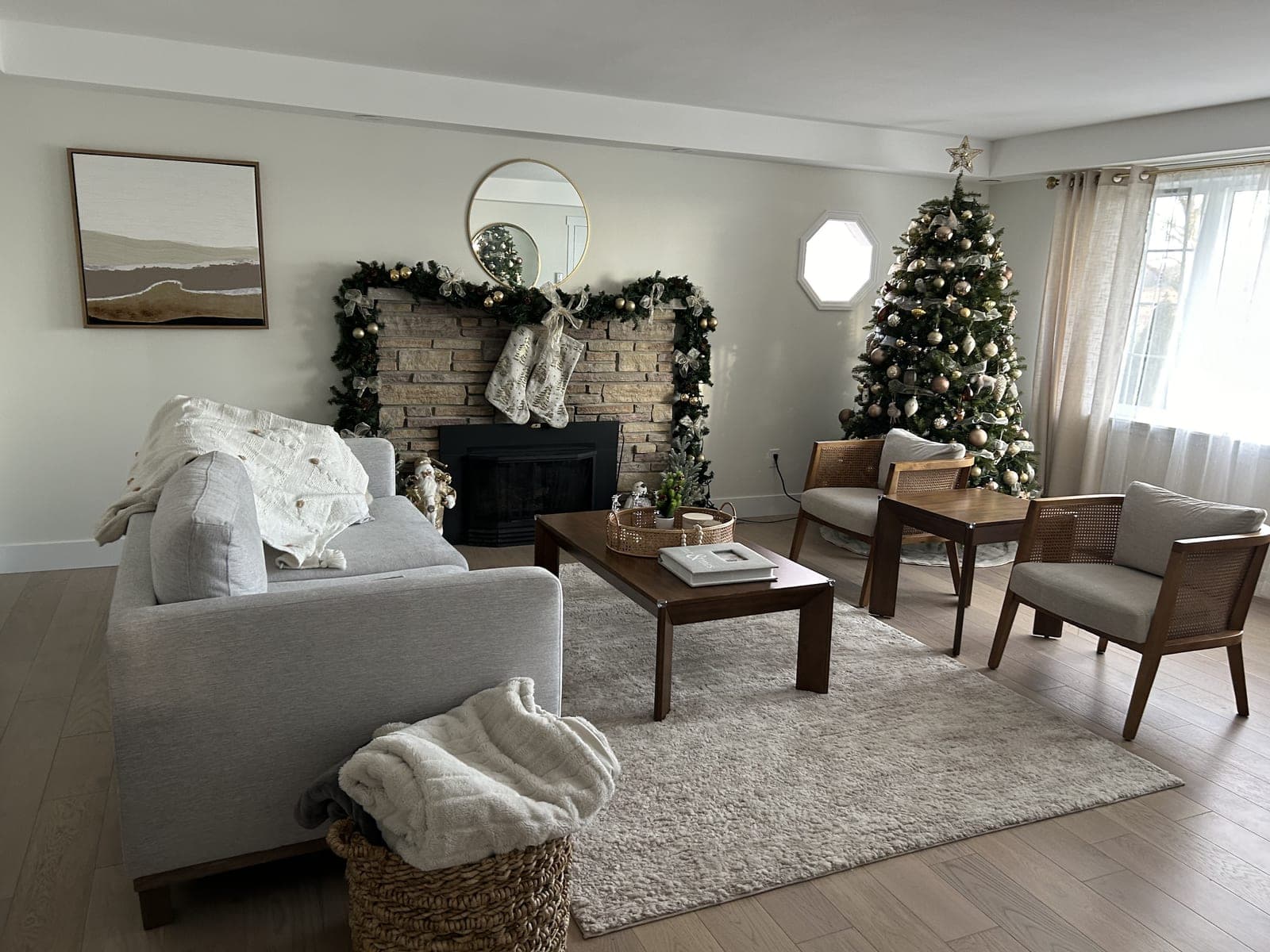 Living room with a decorated Christmas tree beside a fireplace draped in lit garland and stockings