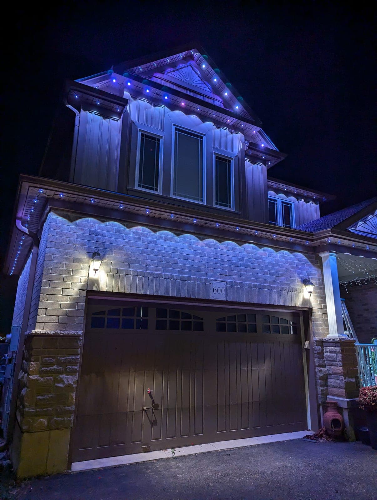 Home garage and gable outlined in blue permanent LED Christmas lights at night