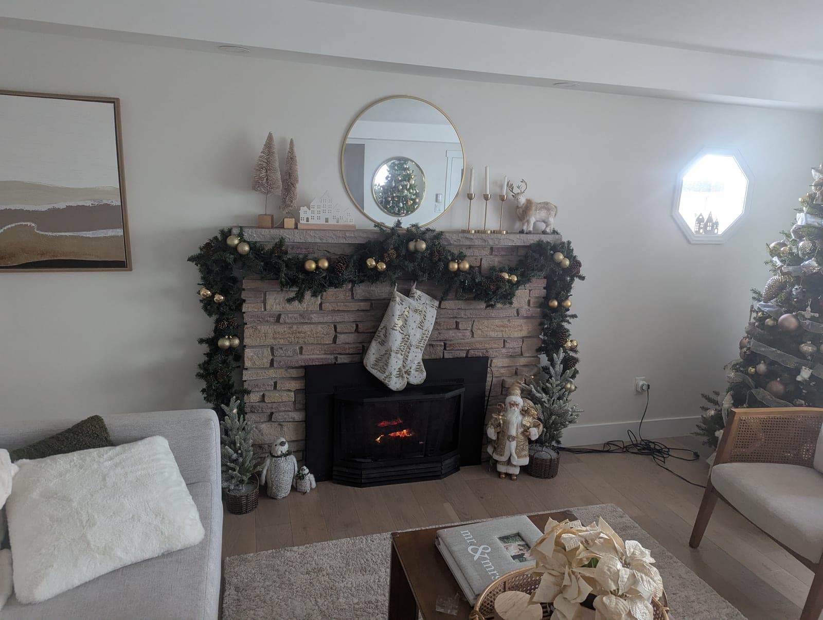 Living room fireplace mantel with lit garland, stockings and a decorated Christmas tree